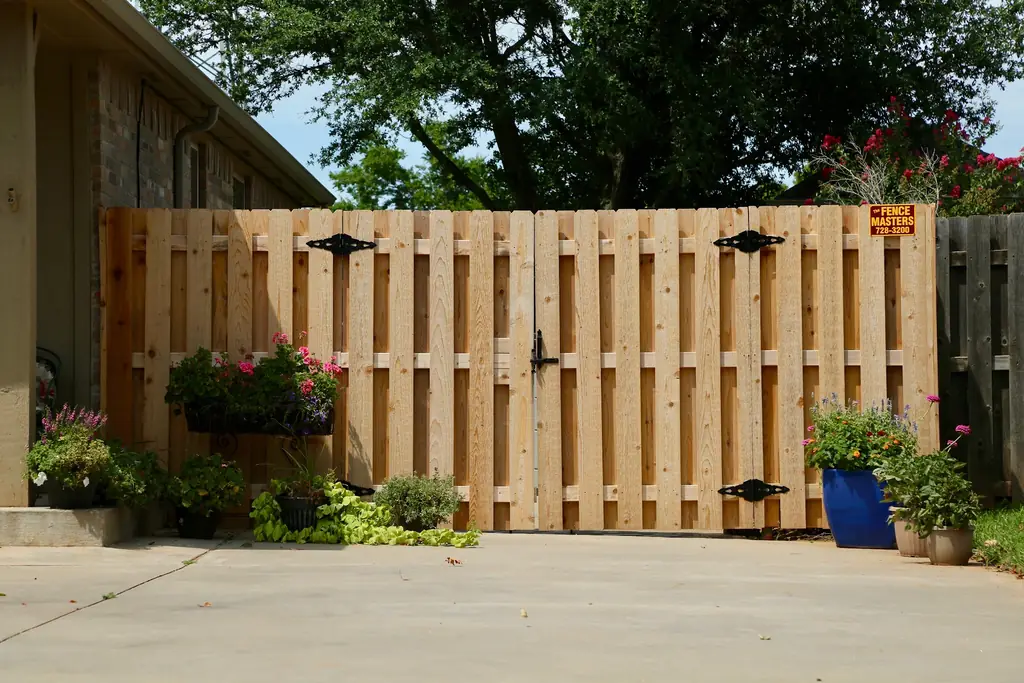 Cedar shadowbox double gate with black ornamental hinges built by Fence Masters