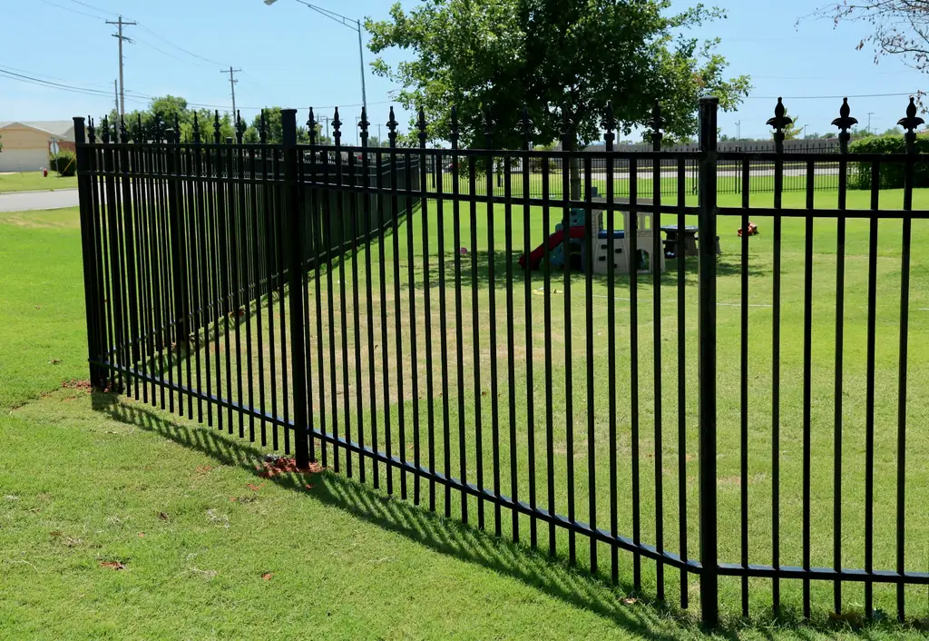 Long run of black ornamental iron fence with finial posts installed by Fence Masters
