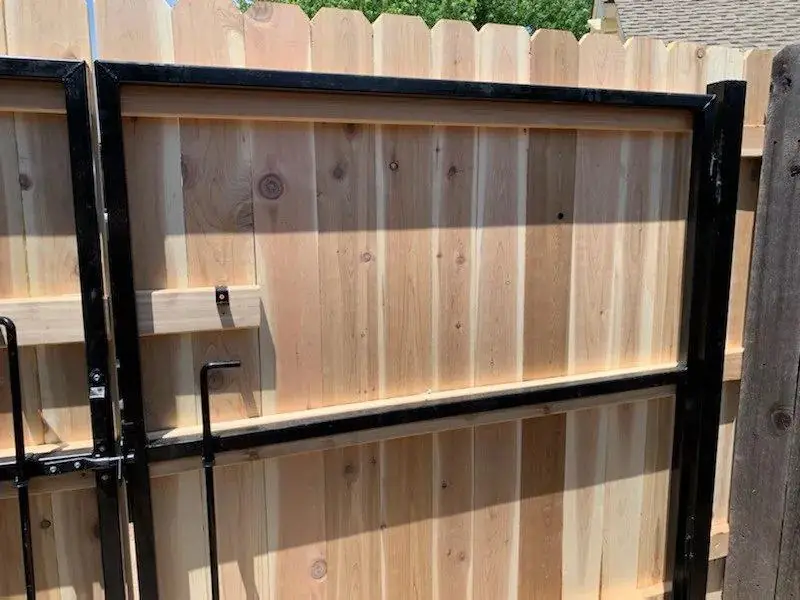 Close detail of a steel-framed cedar gate showing the hardware and brace Fence Masters build in