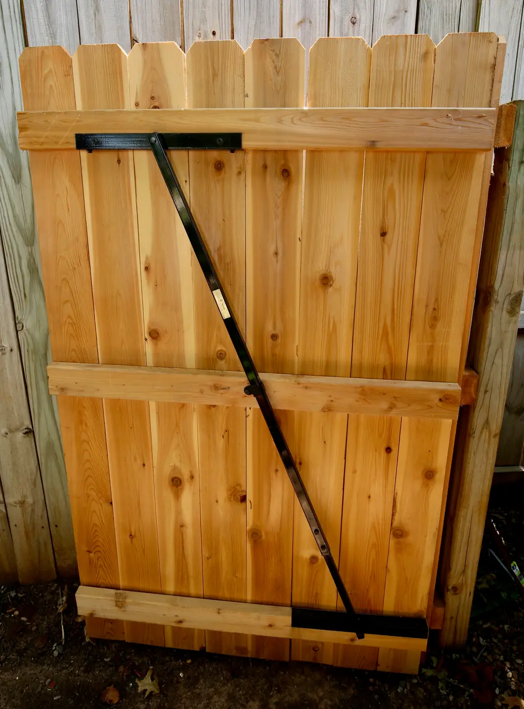 Scalloped-picket cedar gate with an anti-sag steel brace built by Fence Masters